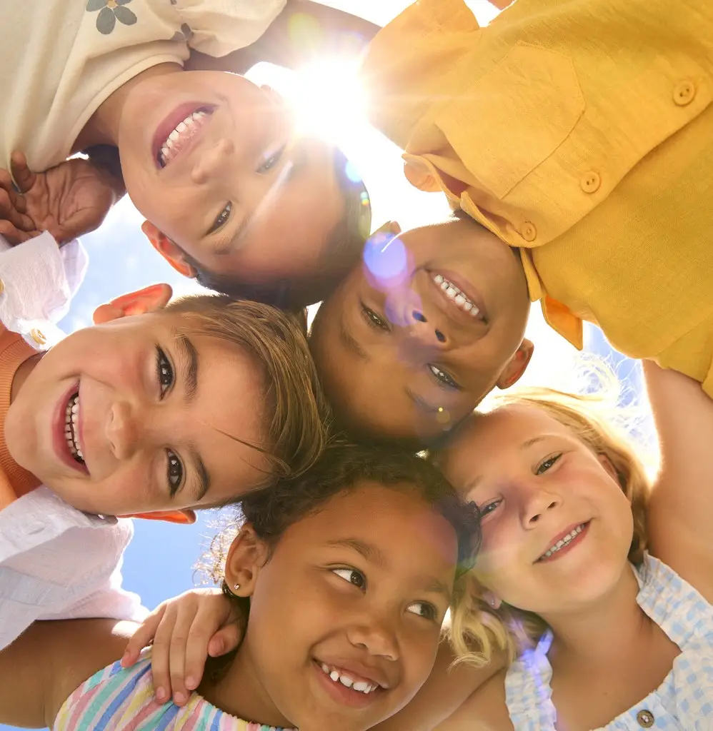Child & Teen Therapy. Group Of Multi-Cultural Children Friends Linking Arms Looking Down Into Camera
