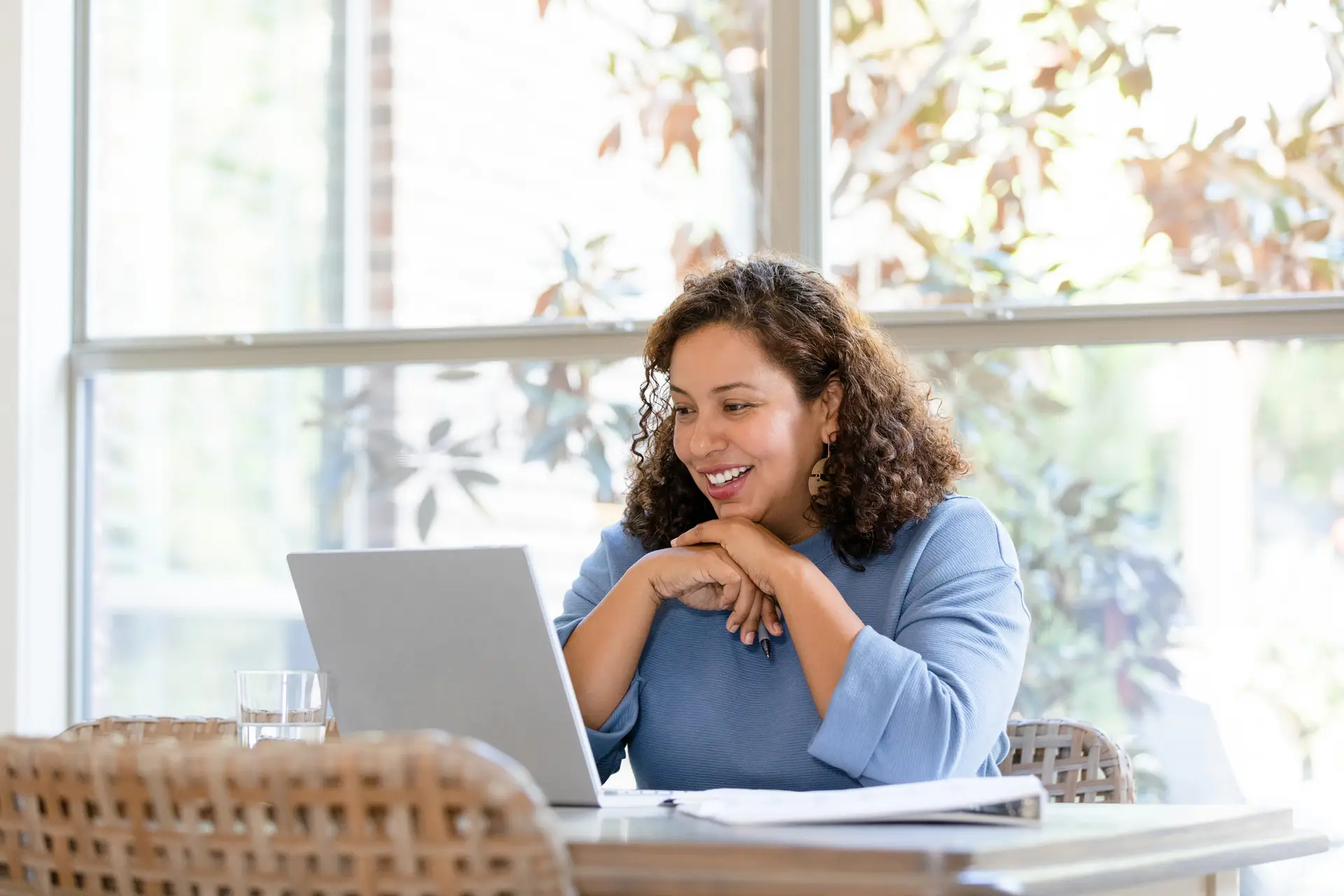 CBT Therapy. The mid adult woman sits at her dining room table to talk to her family on a video call on the laptop.