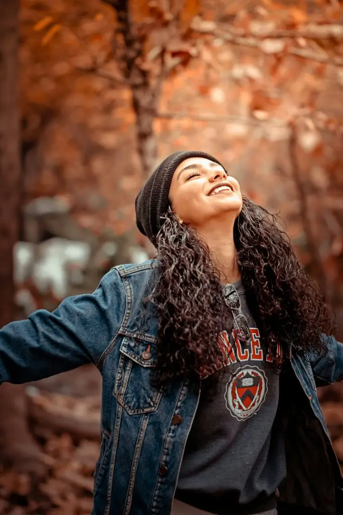 ACT Therapy. Woman in autumn leaves smiling with arms outstretched