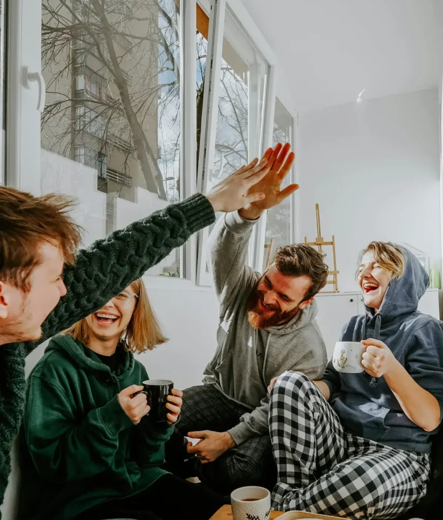 Friends laughing and high-fiving in a living room