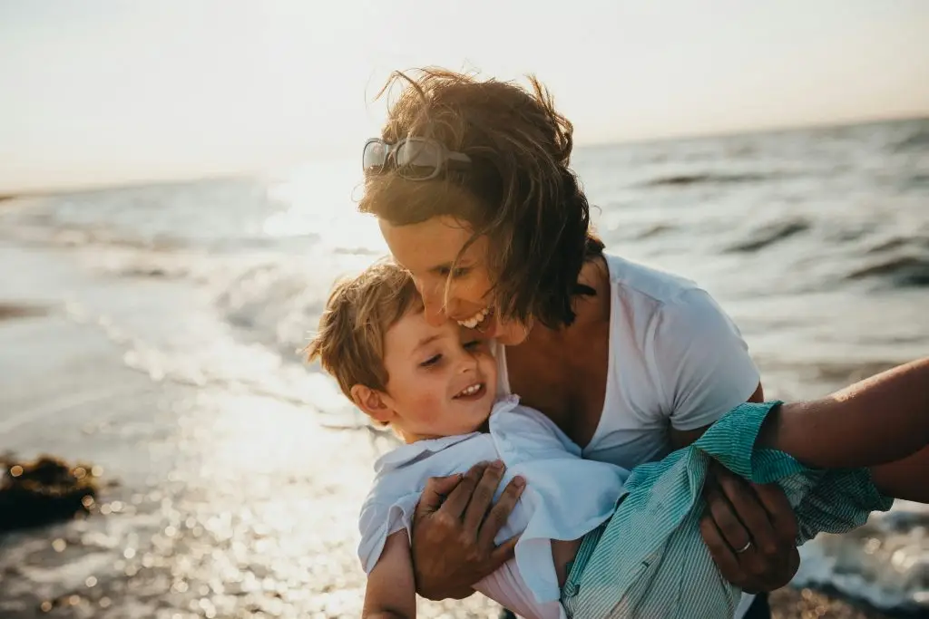 Happy mother hugging her son on the beach.
