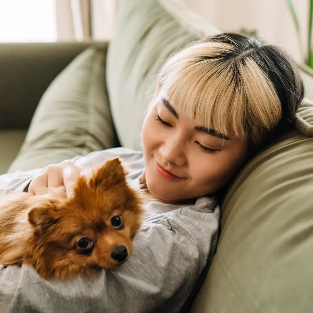 Anxiety Therapy. Girl sitting on a couch and smiling at her dog