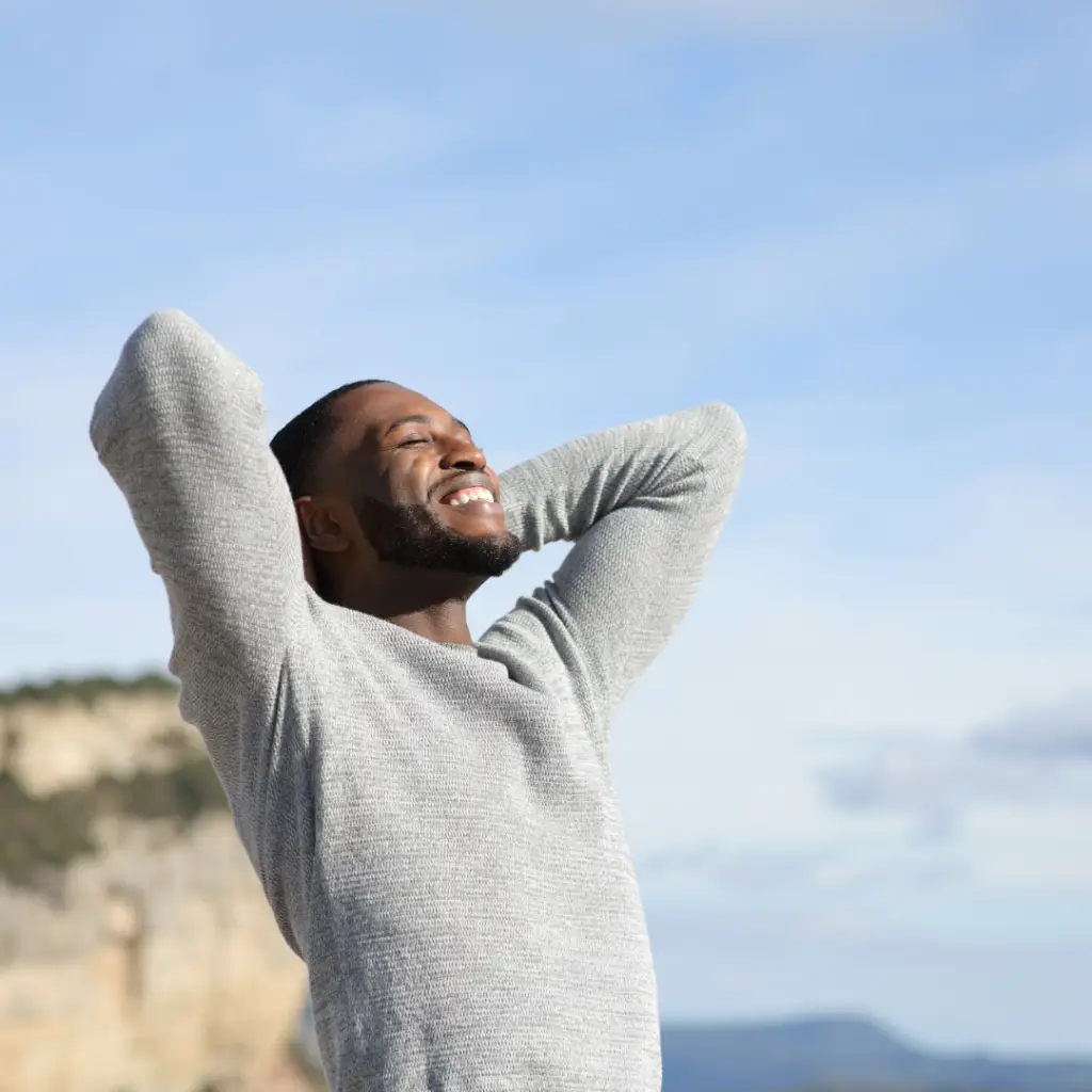 Anxiety Therapy. Man on a beach with his arms up looking relieved