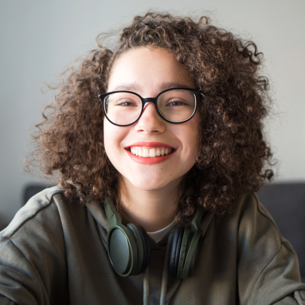 BFRB Therapy. Smiling teen with curly hair wearing headphones around her neck