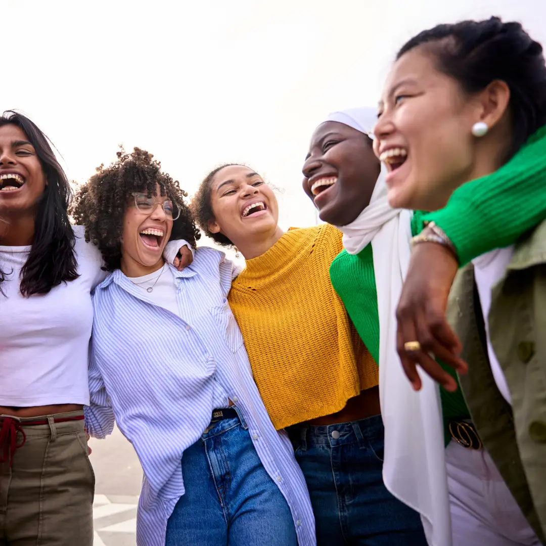 Woman friends laughing with linked arms or arms over shoulders