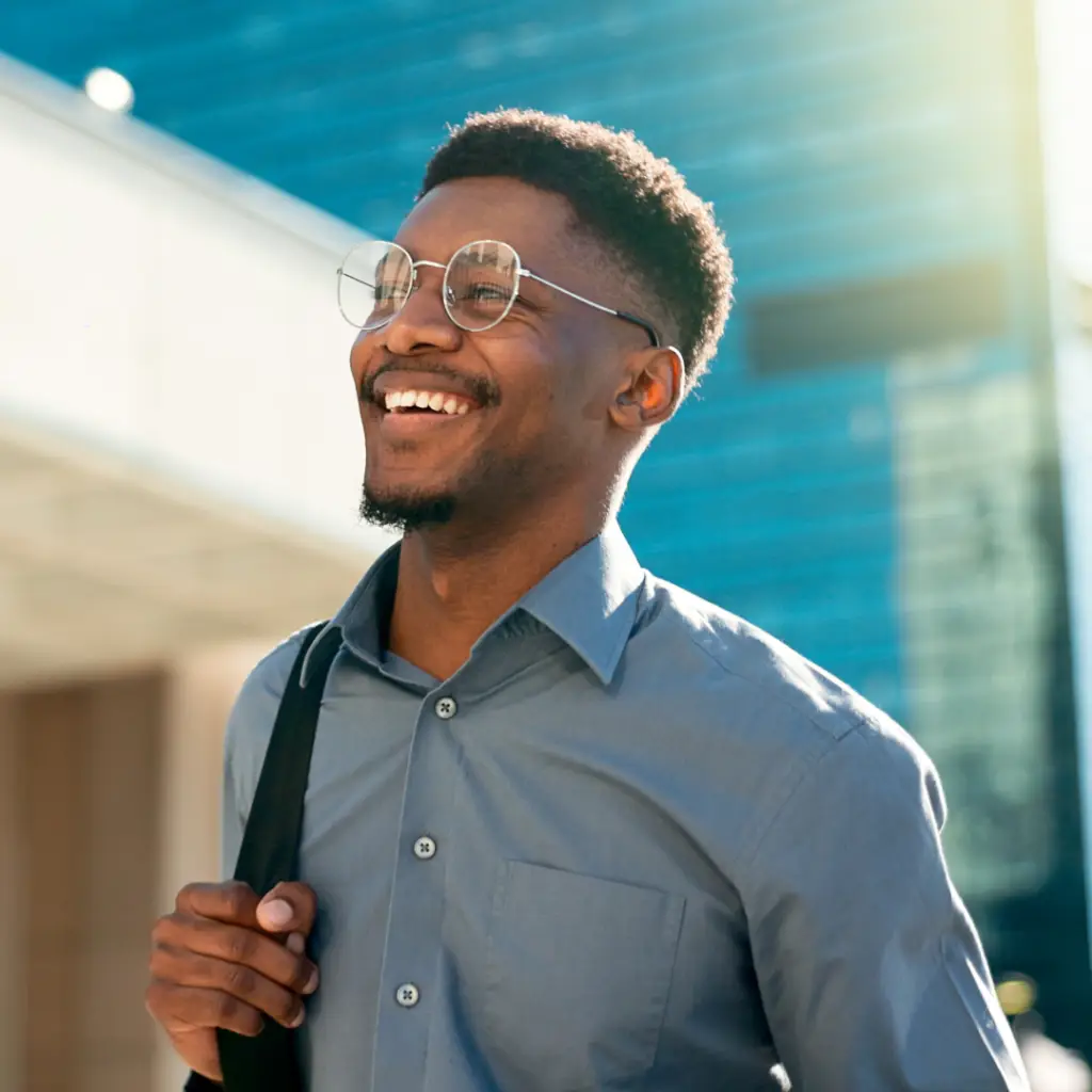 a cheerful man wearing glasses and carrying a backpack