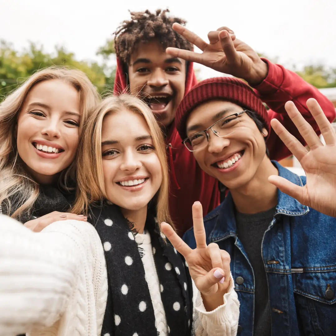 A happy adult friend group hugging and smiling while taking a selfie