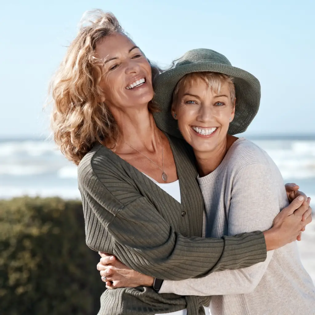Adult women friends hugging and smiling on a beach