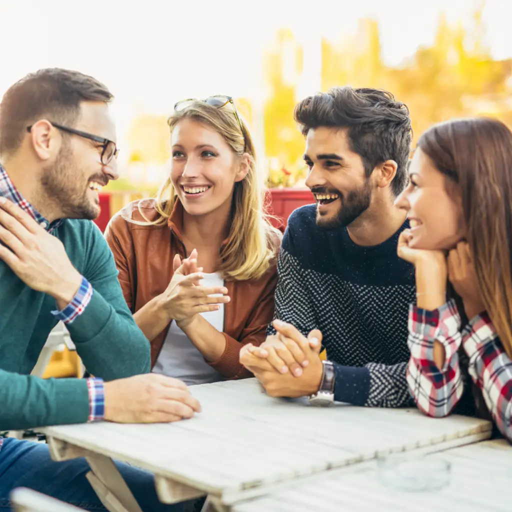 Two men and two women friends smiling and talking at a picnic table