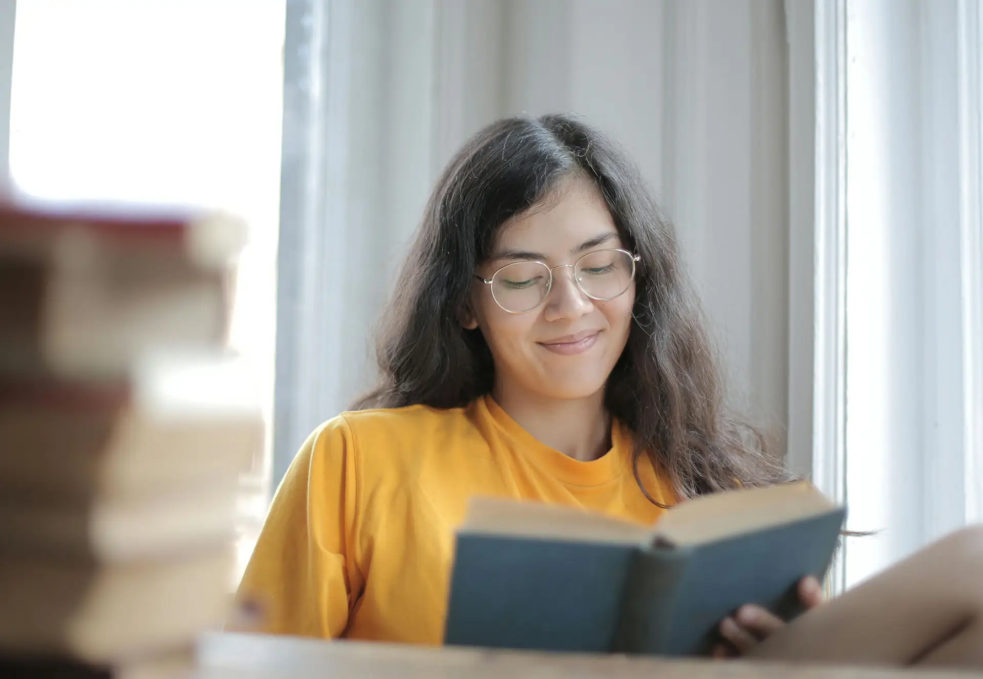 Young woman reading a book by a window in natural light