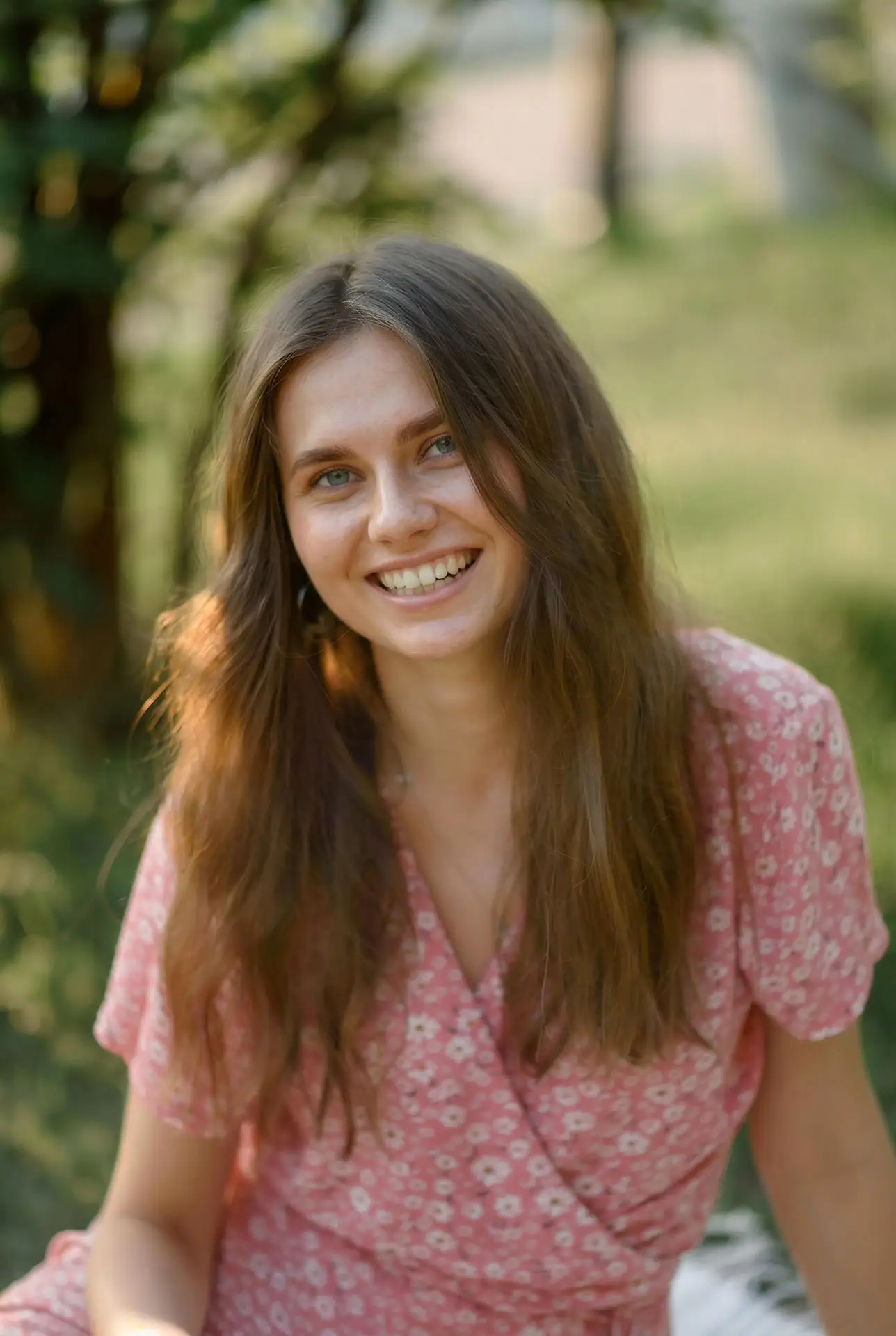 Young woman smiling outdoors in a floral summer dress