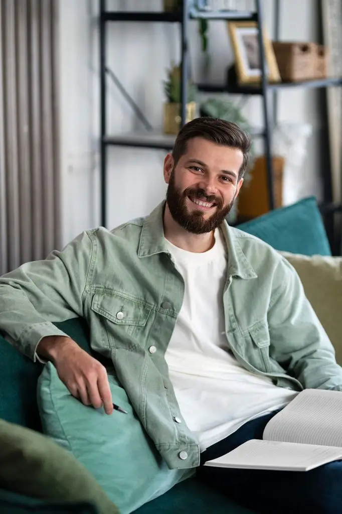 Man relaxing on a sofa with an open notebook