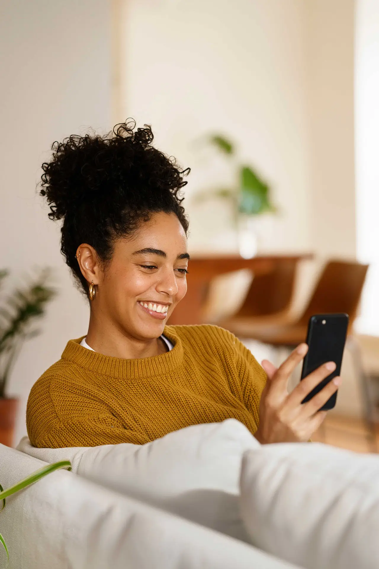 Woman smiling while using her smartphone at home