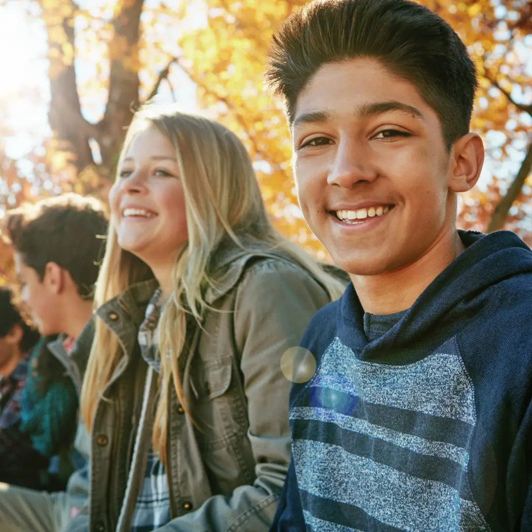 Child & Teen Therapy. A group of teenager sitting and smiling with a forest behind them